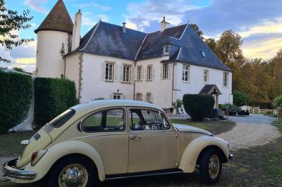 Trampoline rond avec filet de sécurité installé dans un jardin verdoyant, près d'une maison en pierre.