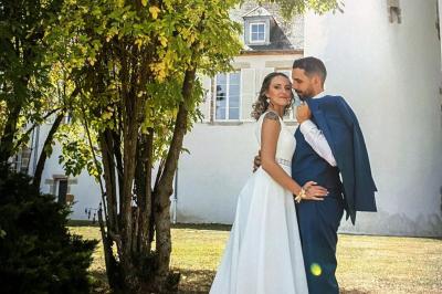 Trampoline rond avec filet de sécurité installé dans un jardin verdoyant, près d'une maison en pierre.