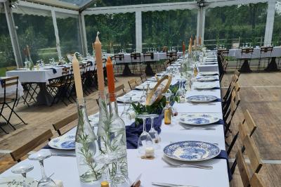 Trampoline rond avec filet de sécurité installé dans un jardin verdoyant, près d'une maison en pierre.