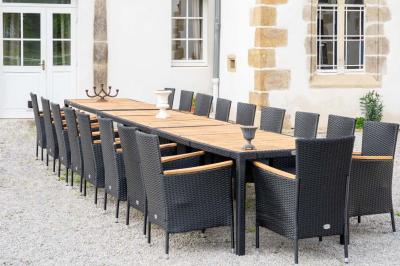 Chambre lumineuse avec deux lits simples, un miroir mural, un fauteuil en osier et un tableau décoratif.