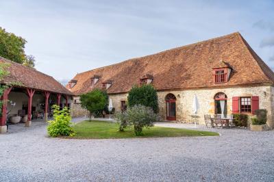 Chambre lumineuse avec deux lits simples, un miroir mural, un fauteuil en osier et un tableau décoratif.