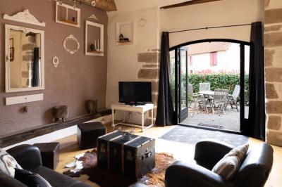 Chambre lumineuse avec deux lits simples, un miroir mural, un fauteuil en osier et un tableau décoratif.