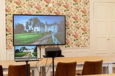 Chambre lumineuse avec deux lits simples, un miroir mural, un fauteuil en osier et un tableau décoratif.