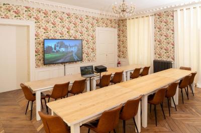 Chambre lumineuse avec deux lits simples, un miroir mural, un fauteuil en osier et un tableau décoratif.