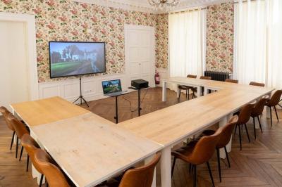 Chambre lumineuse avec deux lits simples, un miroir mural, un fauteuil en osier et un tableau décoratif.