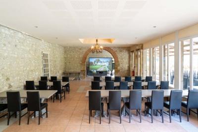 Chambre lumineuse avec deux lits simples, un miroir mural, un fauteuil en osier et un tableau décoratif.