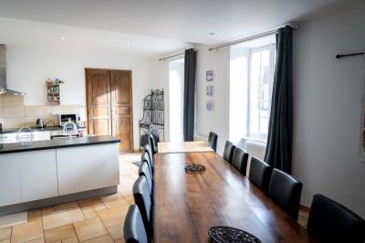 Chambre lumineuse avec deux lits simples, un miroir mural, un fauteuil en osier et un tableau décoratif.