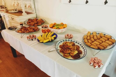 Chambre lumineuse avec deux lits simples, un miroir mural, un fauteuil en osier et un tableau décoratif.