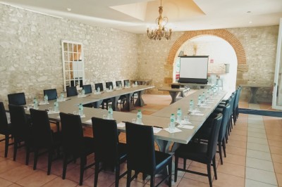 Chambre lumineuse avec deux lits simples, un miroir mural, un fauteuil en osier et un tableau décoratif.