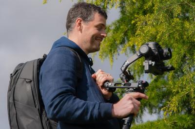Chaussures blanches à talons posées sur un sol en bois, près d'une robe en tissu léger.