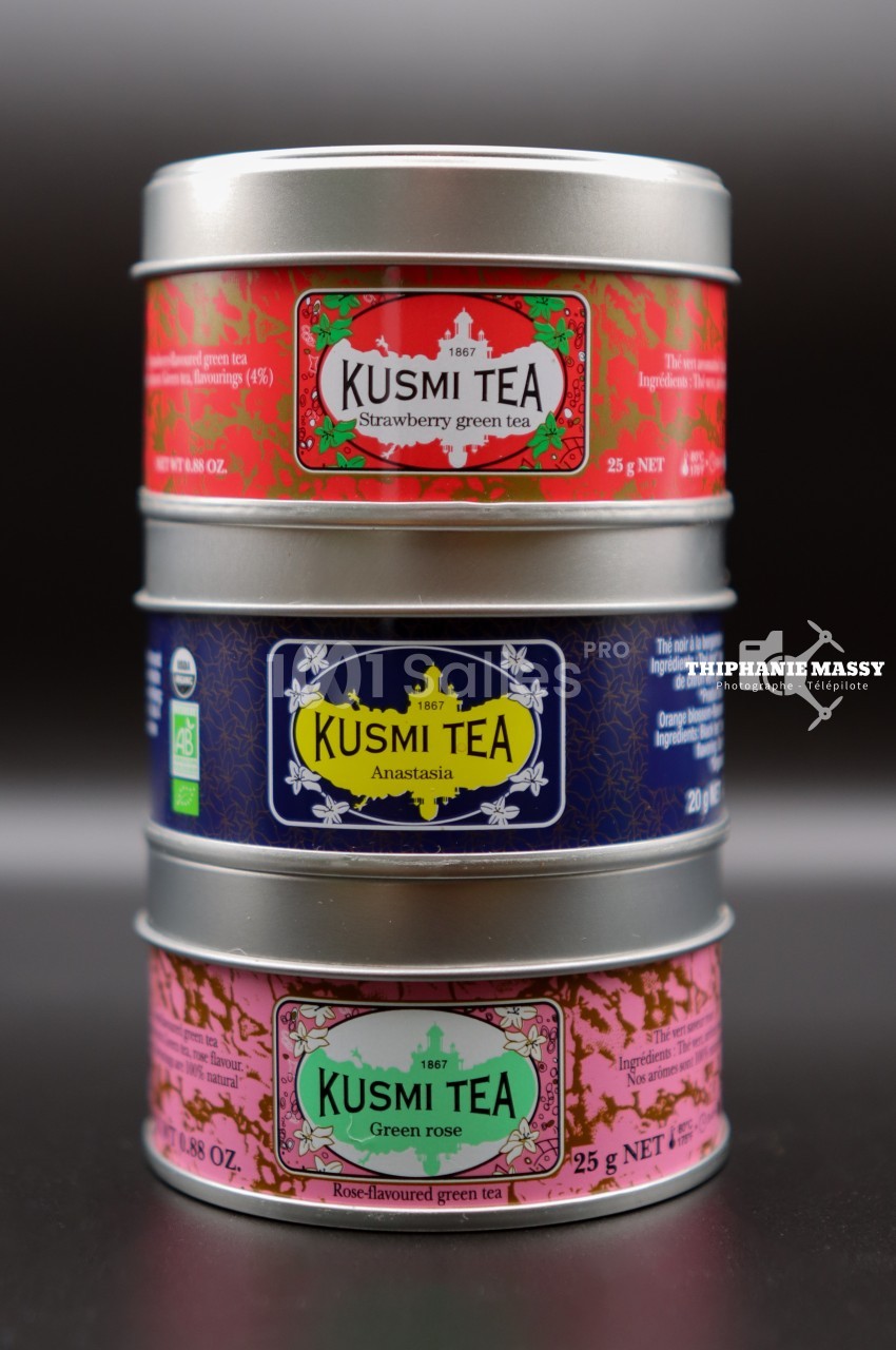 Trois boîtes métalliques empilées de thé Kusmi Tea aux étiquettes colorées indiquant différentes saveurs.