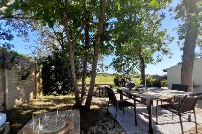 Salle lumineuse avec poutres apparentes, tables dressées et grande baie vitrée donnant sur un extérieur verdoyant.