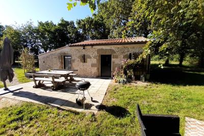 Salle lumineuse avec poutres apparentes, tables dressées et grande baie vitrée donnant sur un extérieur verdoyant.