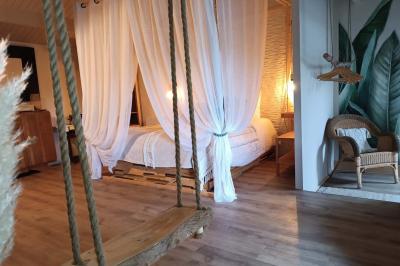 Salle lumineuse avec poutres apparentes, tables dressées et grande baie vitrée donnant sur un extérieur verdoyant.