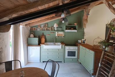 Salle lumineuse avec poutres apparentes, tables dressées et grande baie vitrée donnant sur un extérieur verdoyant.