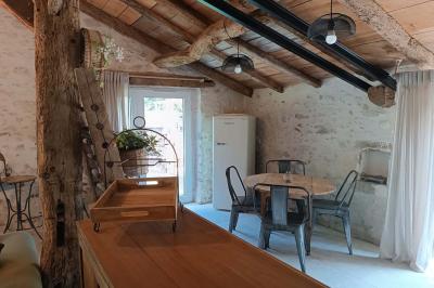 Salle lumineuse avec poutres apparentes, tables dressées et grande baie vitrée donnant sur un extérieur verdoyant.