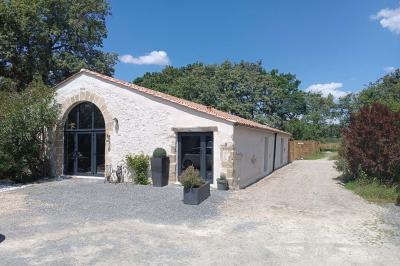 Salle lumineuse avec poutres apparentes, tables dressées et grande baie vitrée donnant sur un extérieur verdoyant.