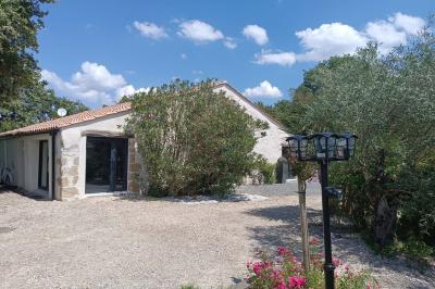 Salle lumineuse avec poutres apparentes, tables dressées et grande baie vitrée donnant sur un extérieur verdoyant.
