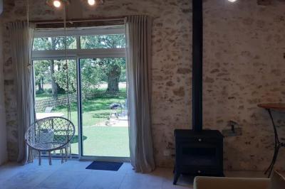 Salle lumineuse avec poutres apparentes, tables dressées et grande baie vitrée donnant sur un extérieur verdoyant.