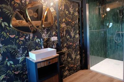 Salle lumineuse avec poutres apparentes, tables dressées et grande baie vitrée donnant sur un extérieur verdoyant.