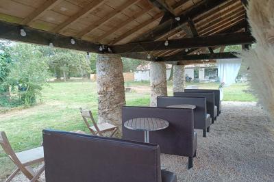 Salle lumineuse avec poutres apparentes, tables dressées et grande baie vitrée donnant sur un extérieur verdoyant.