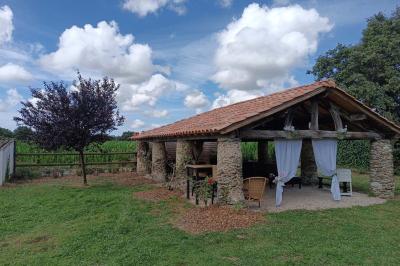Salle lumineuse avec poutres apparentes, tables dressées et grande baie vitrée donnant sur un extérieur verdoyant.