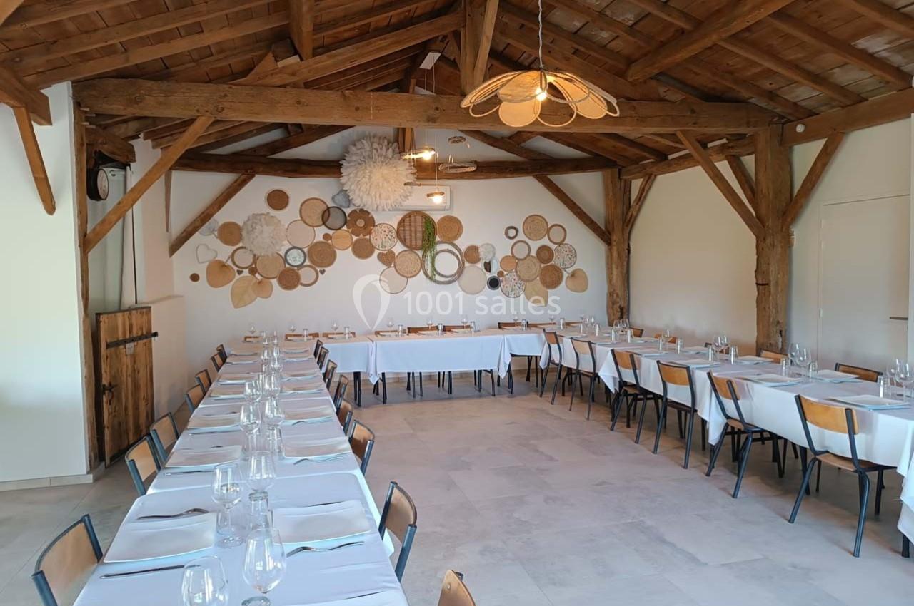 Salle de réception lumineuse avec tables dressées, poutres en bois apparentes et décoration murale en osier.