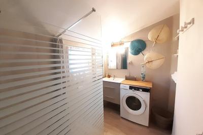 Salle lumineuse avec poutres apparentes, tables dressées et grande baie vitrée donnant sur un extérieur verdoyant.