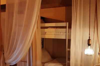 Salle lumineuse avec poutres apparentes, tables dressées et grande baie vitrée donnant sur un extérieur verdoyant.