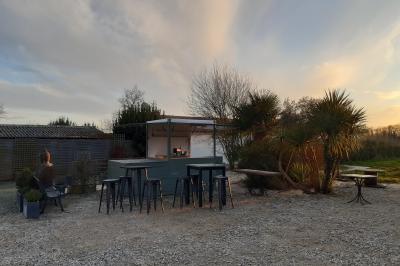 Salle lumineuse avec poutres apparentes, tables dressées et grande baie vitrée donnant sur un extérieur verdoyant.
