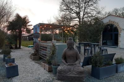 Salle lumineuse avec poutres apparentes, tables dressées et grande baie vitrée donnant sur un extérieur verdoyant.