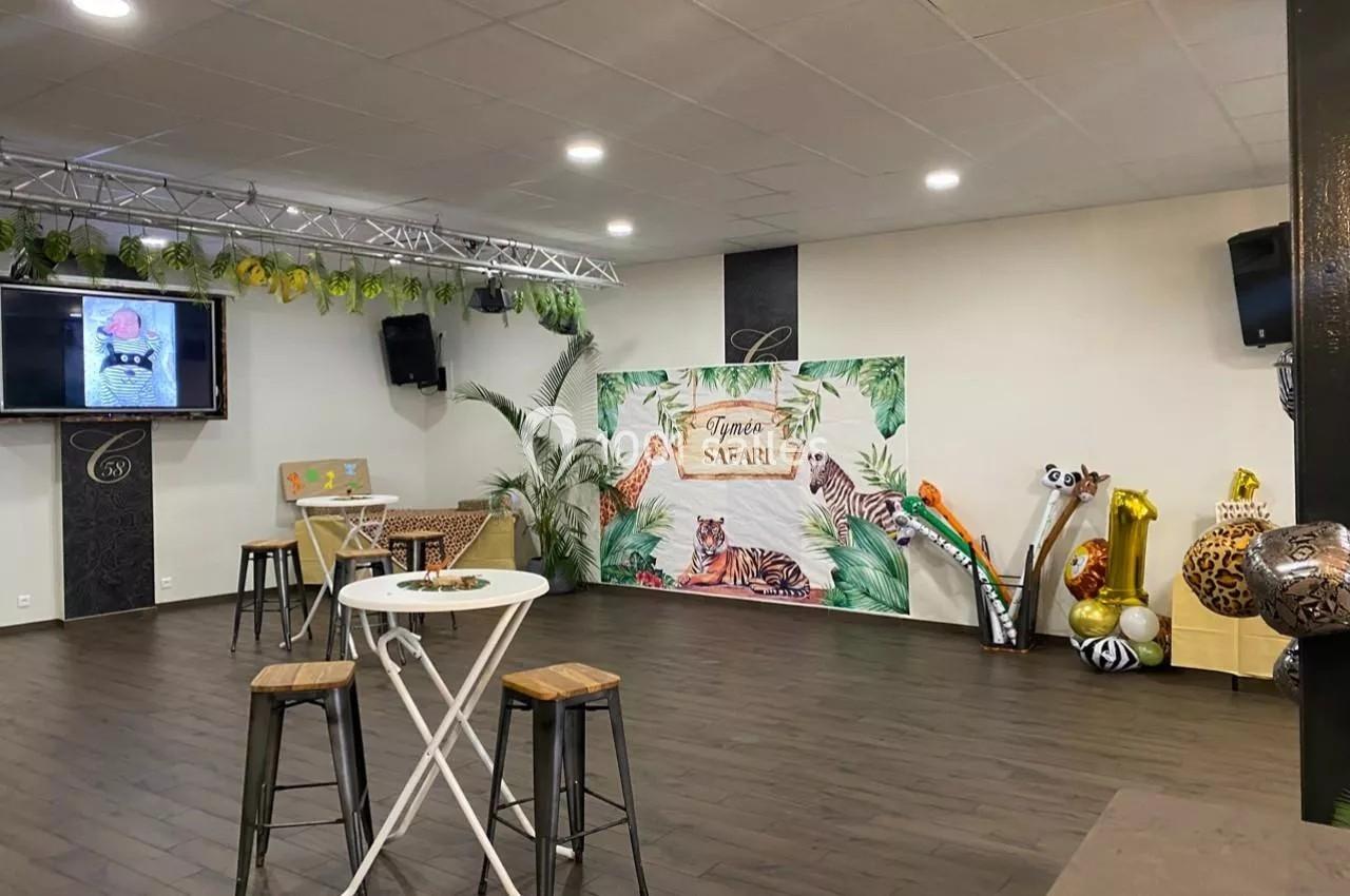Salle décorée sur le thème safari avec plantes, animaux gonflables, table haute et scène équipée d'un écran.