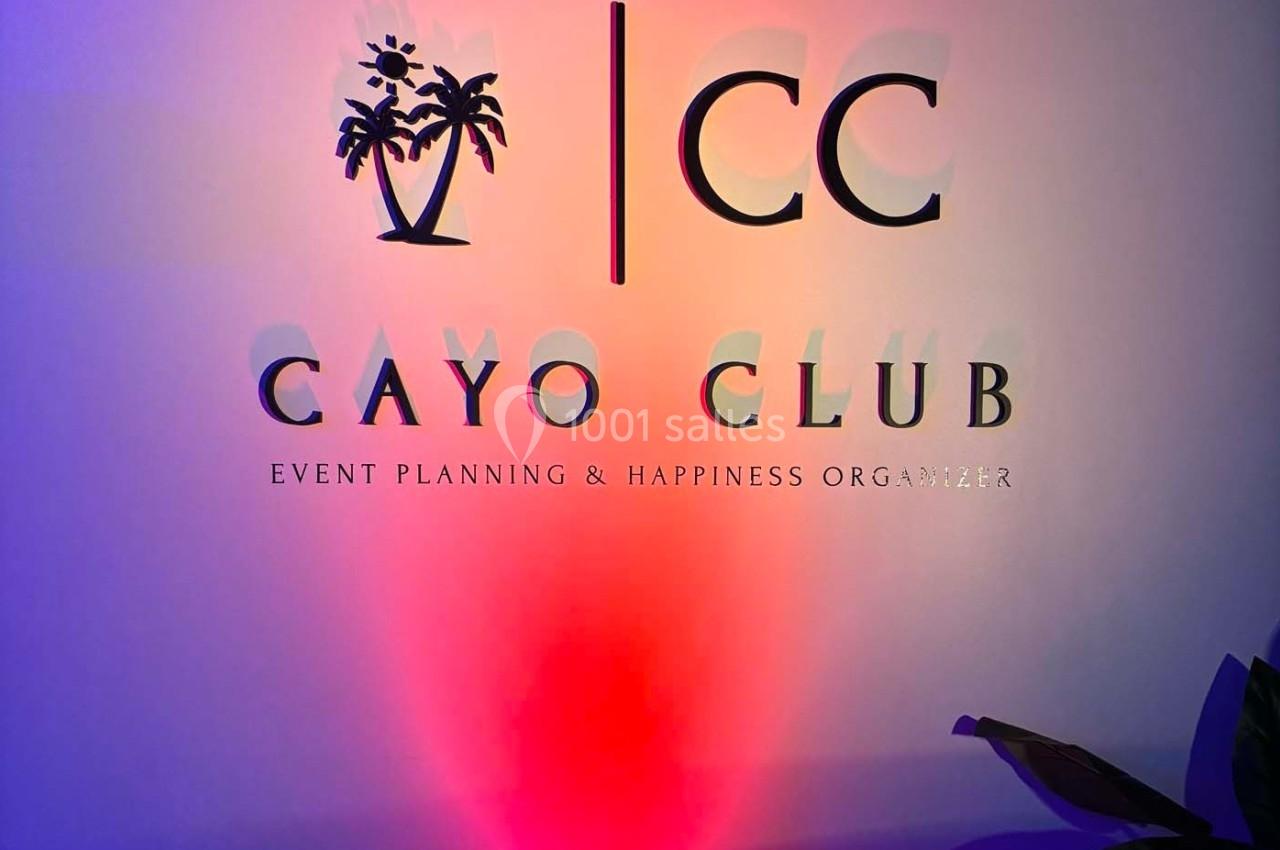 Mur avec le logo ’Cayo Club’, des palmiers stylisés et le slogan ’Event Planning & Happiness Organizer’.