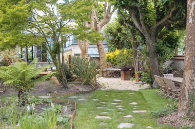 Salle de bain luxueuse avec baignoire en marbre, double vasque, miroirs, et fenêtre donnant sur un jardin.