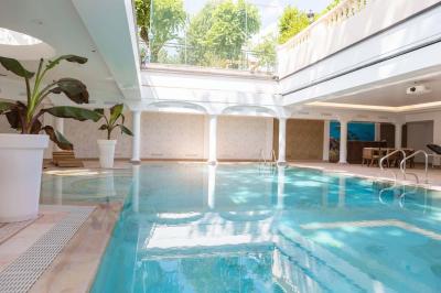 Salle de bain luxueuse avec baignoire en marbre, double vasque, miroirs, et fenêtre donnant sur un jardin.