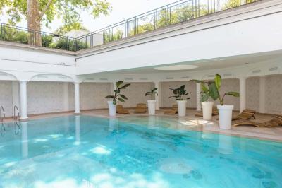 Salle de bain luxueuse avec baignoire en marbre, double vasque, miroirs, et fenêtre donnant sur un jardin.