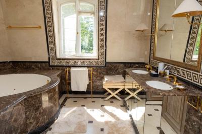 Salle de bain luxueuse avec baignoire en marbre, double vasque, miroirs, et fenêtre donnant sur un jardin.