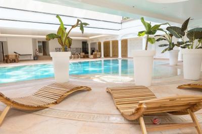 Salle de bain luxueuse avec baignoire en marbre, double vasque, miroirs, et fenêtre donnant sur un jardin.