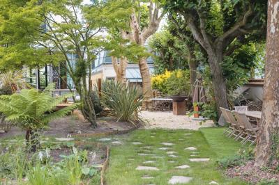 Salle de bain luxueuse avec baignoire en marbre, double vasque, miroirs, et fenêtre donnant sur un jardin.