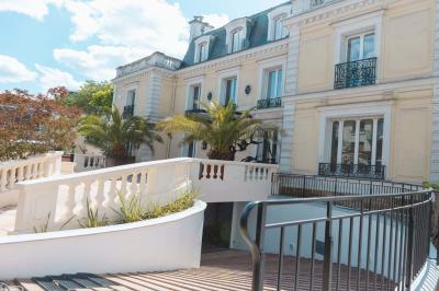 Salle de bain luxueuse avec baignoire en marbre, double vasque, miroirs, et fenêtre donnant sur un jardin.
