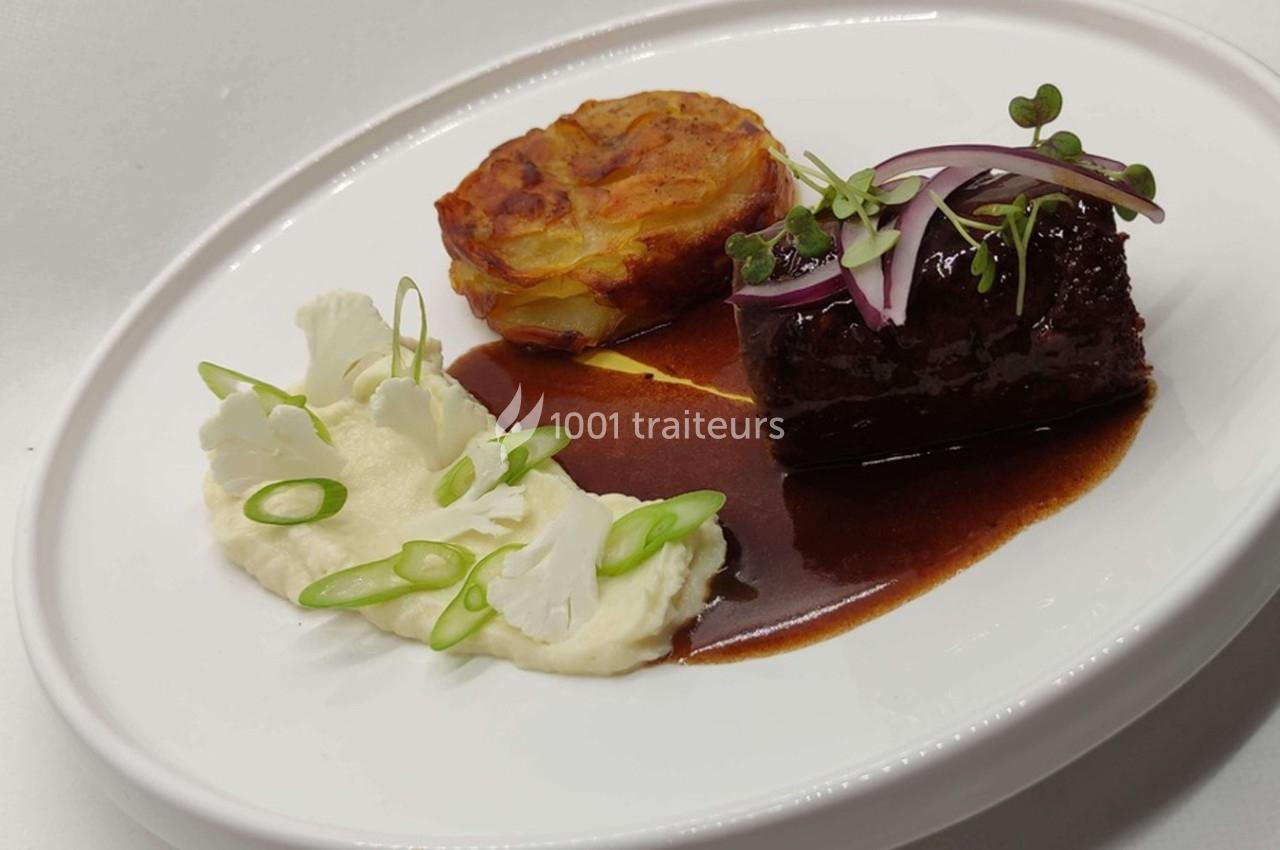 Assiette gastronomique avec viande en sauce, purée, gratin de pommes de terre et garniture de légumes frais.