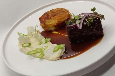 Assiette gastronomique avec viande en sauce, purée, gratin de pommes de terre et garniture de légumes frais.