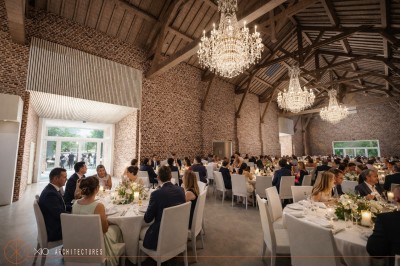 Un couple échange ses vœux sous une arche fleurie lors d'une cérémonie de mariage en plein air, entouré d'invités.
