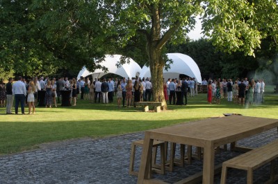Un couple échange ses vœux sous une arche fleurie lors d'une cérémonie de mariage en plein air, entouré d'invités.