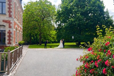 Un couple échange ses vœux sous une arche fleurie lors d'une cérémonie de mariage en plein air, entouré d'invités.