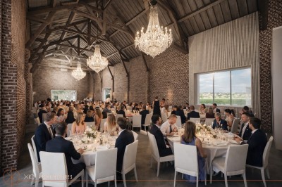 Un couple échange ses vœux sous une arche fleurie lors d'une cérémonie de mariage en plein air, entouré d'invités.