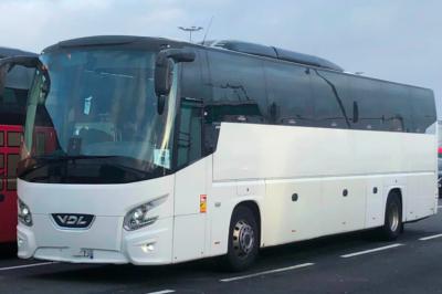 Alignement de plusieurs bus blancs stationnés sur un parking, avec un ciel bleu en arrière-plan.