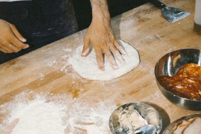 Un homme retire une pizza du four à l'aide d'une pelle, accompagné d'une femme souriante dans une cuisine moderne.
