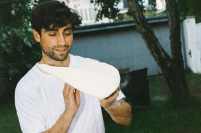 Un homme retire une pizza du four à l'aide d'une pelle, accompagné d'une femme souriante dans une cuisine moderne.