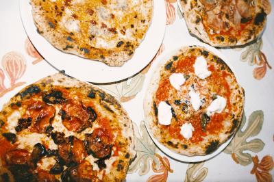Un homme retire une pizza du four à l'aide d'une pelle, accompagné d'une femme souriante dans une cuisine moderne.